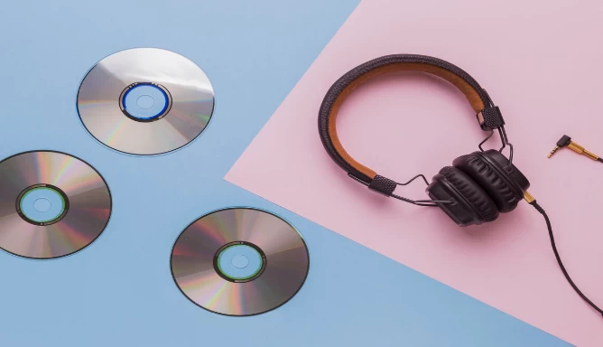 An image of CDs and headphone on a light blue and light pink background.