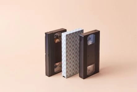 Image of three VHS tapes placed on a pink background.