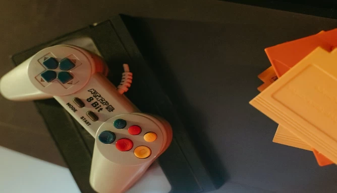 An image of yellow game cartridges and a video game controller on top of a video tape.