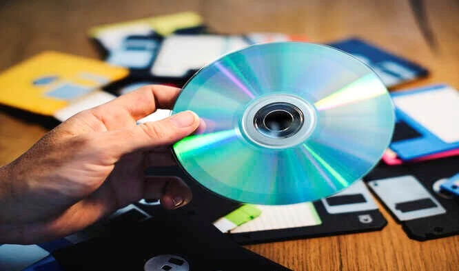 Image of a guy holding a DVD with scattered floppy discs in the background.